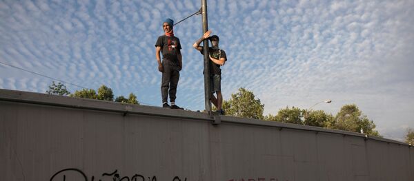 Manifestantes chilenos contra el Gobierno de Chile parados sobre un muro en Santiago - Sputnik Mundo