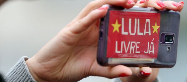 Una mujer sostiene un teléfono celular con un mensaje en apoyo a Lula - Sputnik Mundo