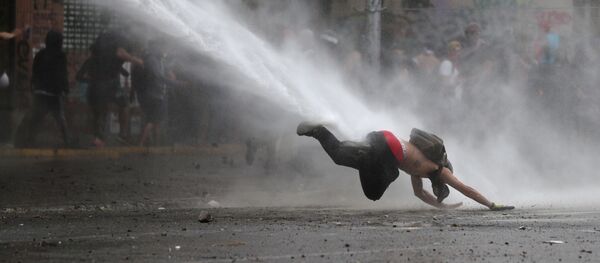 Un manifestante cae al piso por un tanque de agua durante las protestas en Chile - Sputnik Mundo