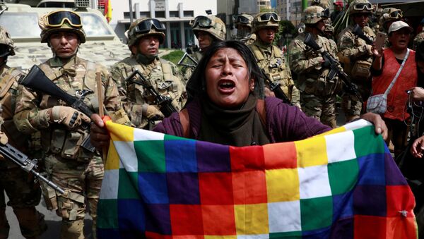 Un manifestante con una bandera de Wiphala frente a miembros de las fuerzas de seguridad durante los enfrentamientos entre partidarios del expresidente boliviano, Evo Morales, y las fuerzas de seguridad en La Paz (Bolivia). - Sputnik Mundo