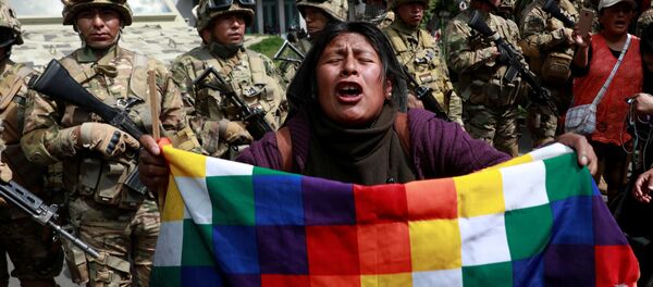 Un manifestante con una bandera de Wiphala frente a miembros de las fuerzas de seguridad durante los enfrentamientos entre partidarios del expresidente boliviano, Evo Morales, y las fuerzas de seguridad en La Paz (Bolivia). - Sputnik Mundo