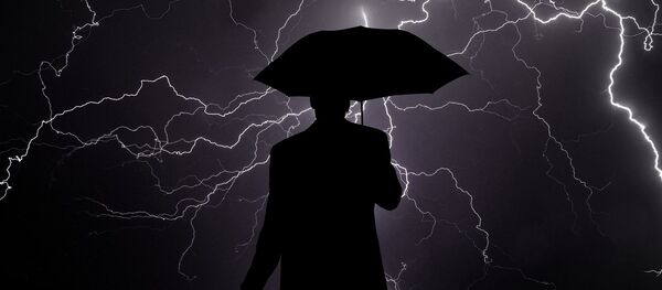 Los rayos y la sombra de una persona con paraguas - Sputnik Mundo