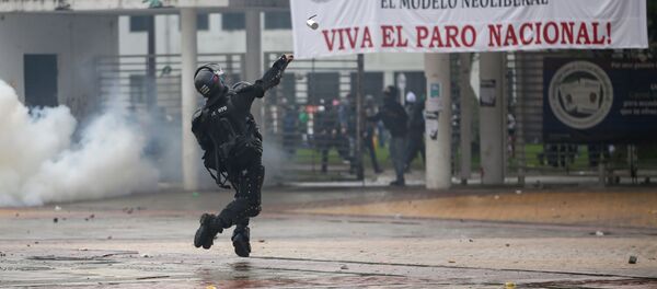 Un policía arroja una bomba de gas a manifestantes durante el paro nacional del 21 de noviembre de 2019 en Bogotá - Sputnik Mundo