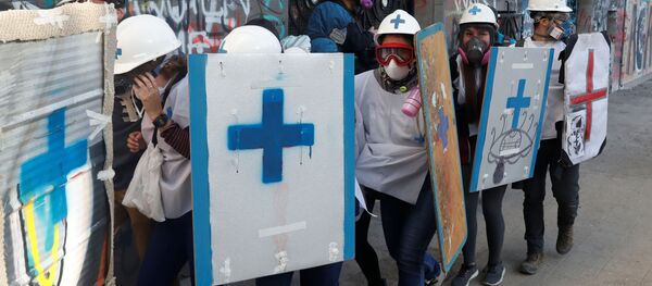 Paramédicos se protegen durante las manifestaciones de protesta en Chile Paramédicos se protegen durante las manifestaciones de protesta en Chile - Sputnik Mundo