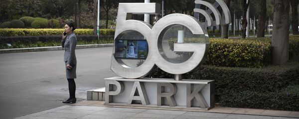 Una empleada de Huawei habla por teléfono cerca de un monumento a la tecnología 5G - Sputnik Mundo