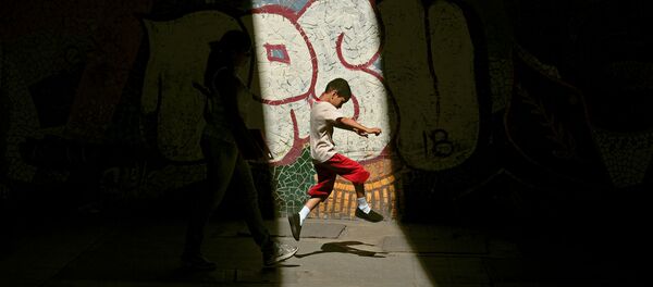 Niño atraviesa espacio iluminado por el sol entre áreas de sombra - Sputnik Mundo