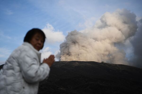 Женщина на фоне действующего вулкана в городе Асо в префектуре Кумамото - Sputnik Mundo