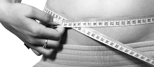 Una mujer mide su cintura - Sputnik Mundo