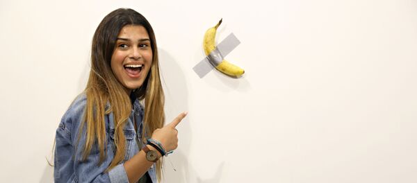 Una visitante de la exposición al lado de la obra 'Comediante' del artista italiano Maurizio Cattelan - Sputnik Mundo