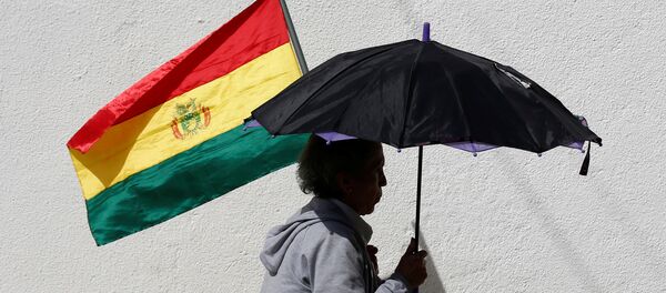 Una mujer con un paraguas y una bandera de Bolivia Una mujer con un paraguas y una bandera de Bolivia - Sputnik Mundo