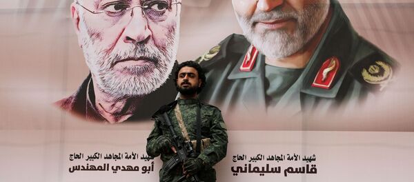 Un militar con el fondo del retrato del general Soleimani - Sputnik Mundo