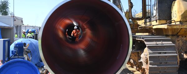 Un trabajador es visto a través de una tubería en el sitio de construcción del gasoducto Nord Stream 2 en Rusia  - Sputnik Mundo