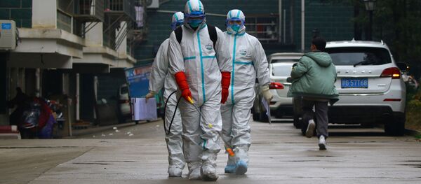 Unos trabajadores del departamento de control y prevención de enfermedades de la provincia china de Jiangxi desinfectan un área residencial después del brote de un nuevo coronavirus - Sputnik Mundo