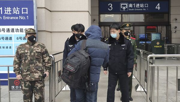 Funcionarios chinos con tapabocas controlan a los pasajeros en la Estación de Tren de Wuhan, tras la cuarentena por coronavirus - Sputnik Mundo