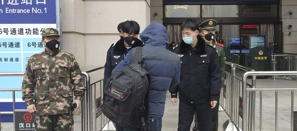 Funcionarios chinos con tapabocas controlan a los pasajeros en la Estación de Tren de Wuhan, tras la cuarentena por coronavirus - Sputnik Mundo