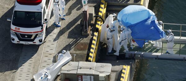 Сотрудники полиции в защитных костюмах помещают в машину скорой помощи заболевшего пассажира круизного лайнера Diamond Princes, помещенного в карантин у японского порта Йокогама - Sputnik Mundo