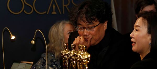 El director surcoreano Bong Joon-Ho mirando las estatuillas ganadas en la ceremonia de los Óscar 2020 - Sputnik Mundo