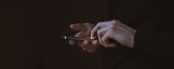 Una persona sostiene un teléfono en sus manos - Sputnik Mundo