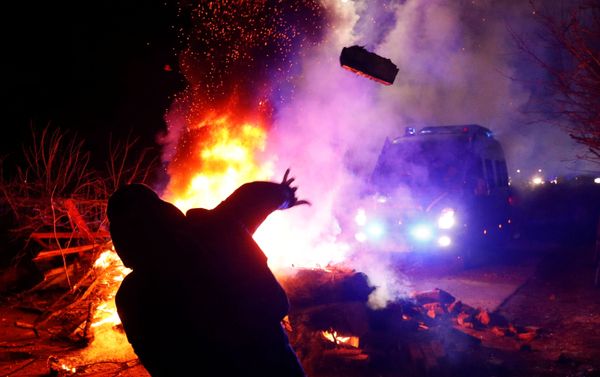 Un manifestante lanza una piedra hacia una camioneta de la Policía durante una protesta contra la llegada de un avión que transportaba evacuados de China - Sputnik Mundo
