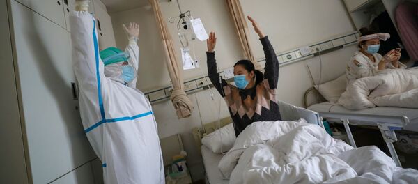 Un médico junto a una paciente en un hospital de Wuhan, China - Sputnik Mundo