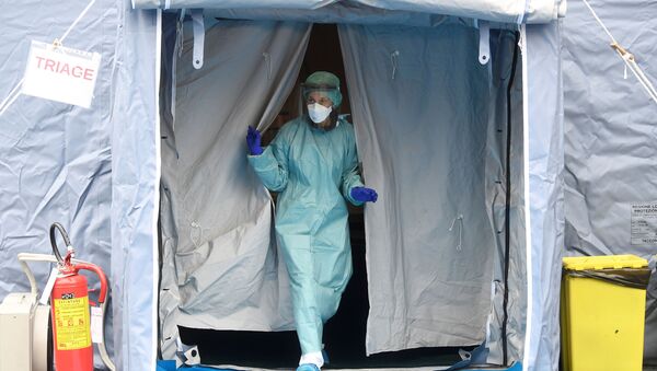 Personal médico en un traje protector y una mascarilla - Sputnik Mundo