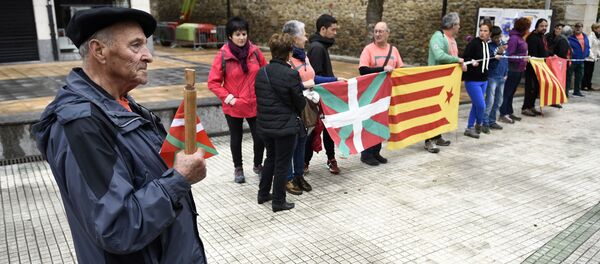 Un señor sostiene un bastón con la bandera vasca al lado de personas que llevan la catalana - Sputnik Mundo
