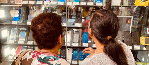 Dos mujeres miran un expositor de celulares en una tienda de Caracas - Sputnik Mundo