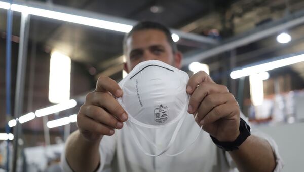 Un hombre sujetando una mascarilla - Sputnik Mundo