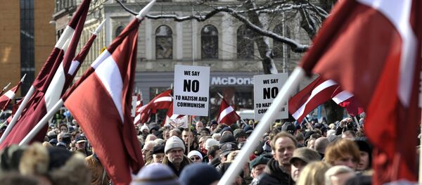 La gente con las banderas de Letonia para conmemorar a los veteranos de la Legión Letona del cuerpo armado de Waffen-SS - Sputnik Mundo