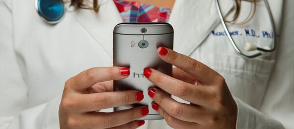 Una doctora con un móvil (imagen referencial) - Sputnik Mundo