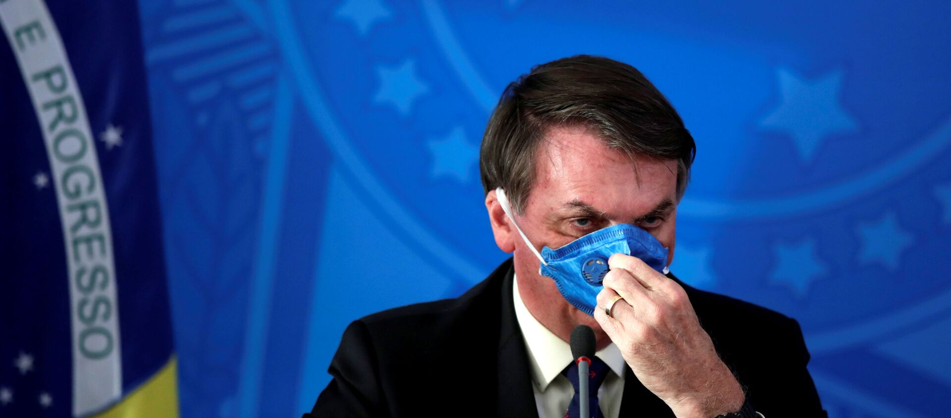 El presidente de Brasil Jair Bolsonaro acomodando una mascarilla - Sputnik Mundo, 1920, 27.03.2020