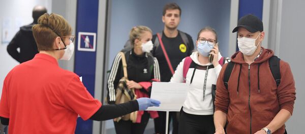 Unos turistas con mascarillas en un aeropuerto Unos turistas con mascarillas en un aeropuerto - Sputnik Mundo