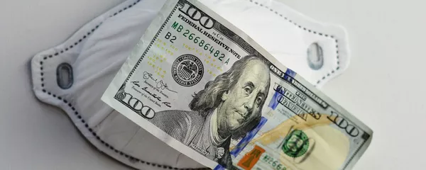 Una mascarilla junto a un billete de 100 dólares. Imagen referencial Una mascarilla junto a un billete de 100 dólares. Imagen referencial - Sputnik Mundo