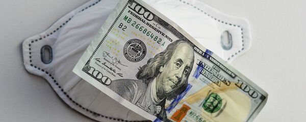 Una mascarilla junto a un billete de 100 dólares. Imagen referencial - Sputnik Mundo