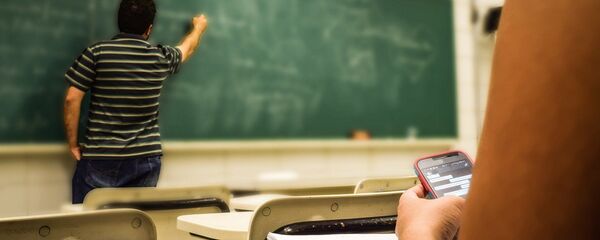 Una estudiante con el móvil da clase en un aula Una estudiante con el móvil da clase en un aula - Sputnik Mundo