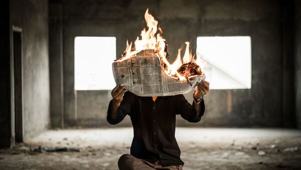 Un hombre con el periódico ardiente (imagen referencial) - Sputnik Mundo