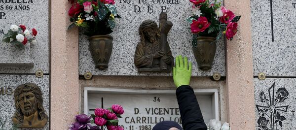 Un hombre cerca de la tumba de sus padres tras la muerte de su madre del coronavirus en España - Sputnik Mundo