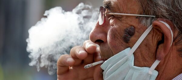 Hombre con mascarilla fumando Hombre con mascarilla fumando - Sputnik Mundo