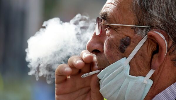 Hombre con mascarilla fumando - Sputnik Mundo
