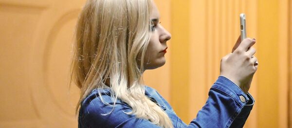 Una chica haciendo una foto con un teléfono móvil Una chica haciendo una foto con un teléfono móvil - Sputnik Mundo