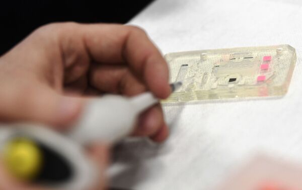 El empleado inyecta el biomaterial al chip del nuevo sistema de pruebas de coronavirus - Sputnik Mundo