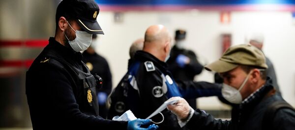 Un policía y un hombre con mascarillas en Madrid durante el brote del coronavirus - Sputnik Mundo