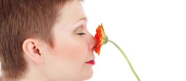 Una mujer huele una una flor - Sputnik Mundo