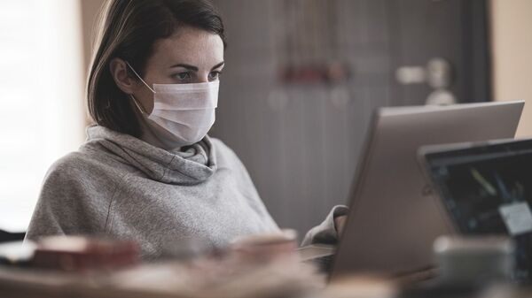 Mujer con mascarilla frente a computadora - Sputnik Mundo