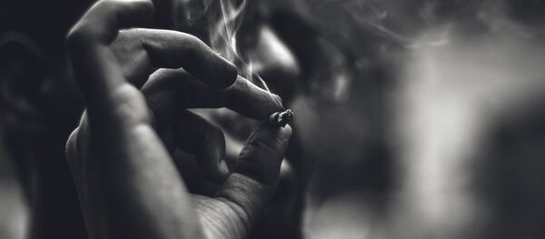 Un hombre fuma un cigarrillo - Sputnik Mundo