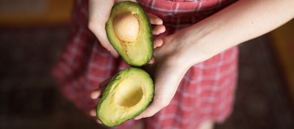 Una persona sostiene un aguacate - Sputnik Mundo