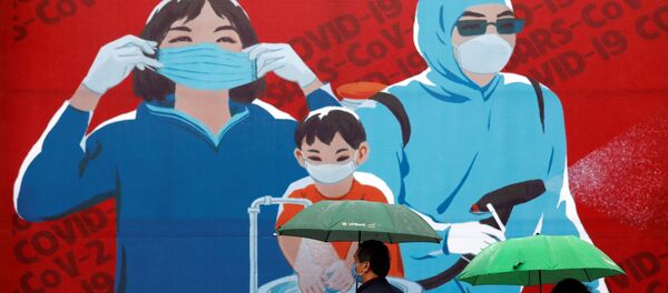 Personas con mascarillas pasan al lado de una pintura que promueve la prevención contra el COVID-19 en Hanoi, Vietnam - Sputnik Mundo