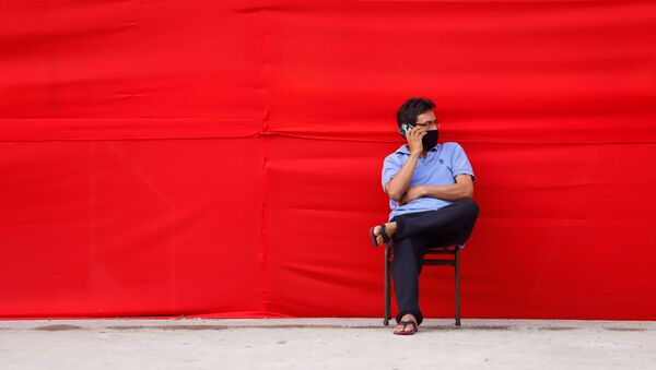 Un hombre en mascarilla hablando por teléfono - Sputnik Mundo