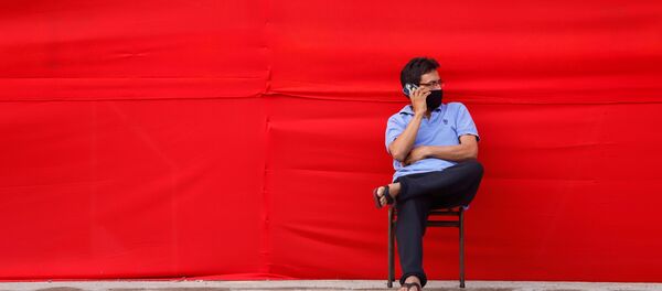 Un hombre en mascarilla hablando por teléfono - Sputnik Mundo