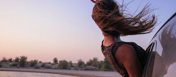 Una joven se asoma por la ventanilla de un coche - Sputnik Mundo